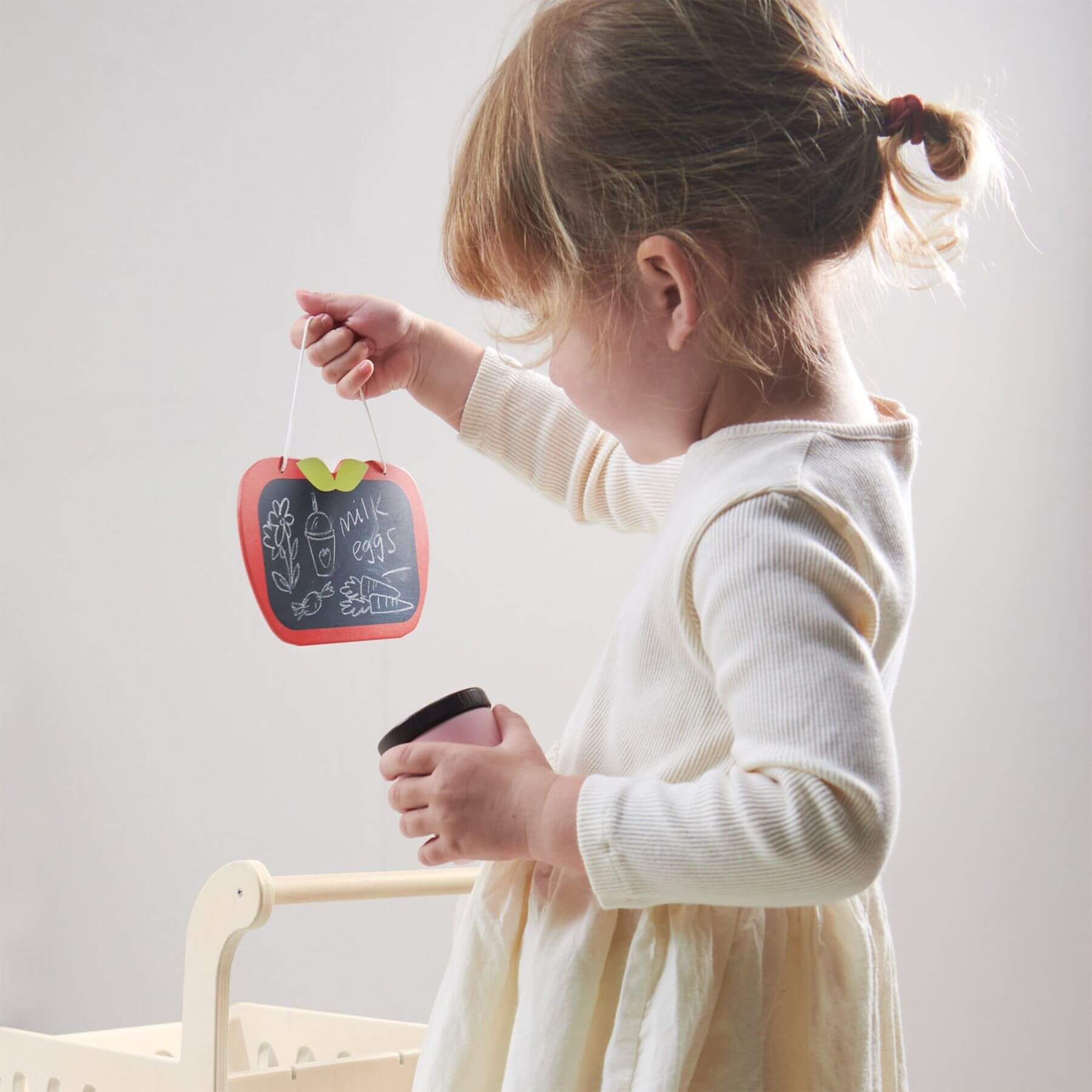 Child holding a small apple-shaped chalkboard with a white background