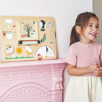 Child standing next to Tender Leaf Weather Watch on a pink fireplace.
