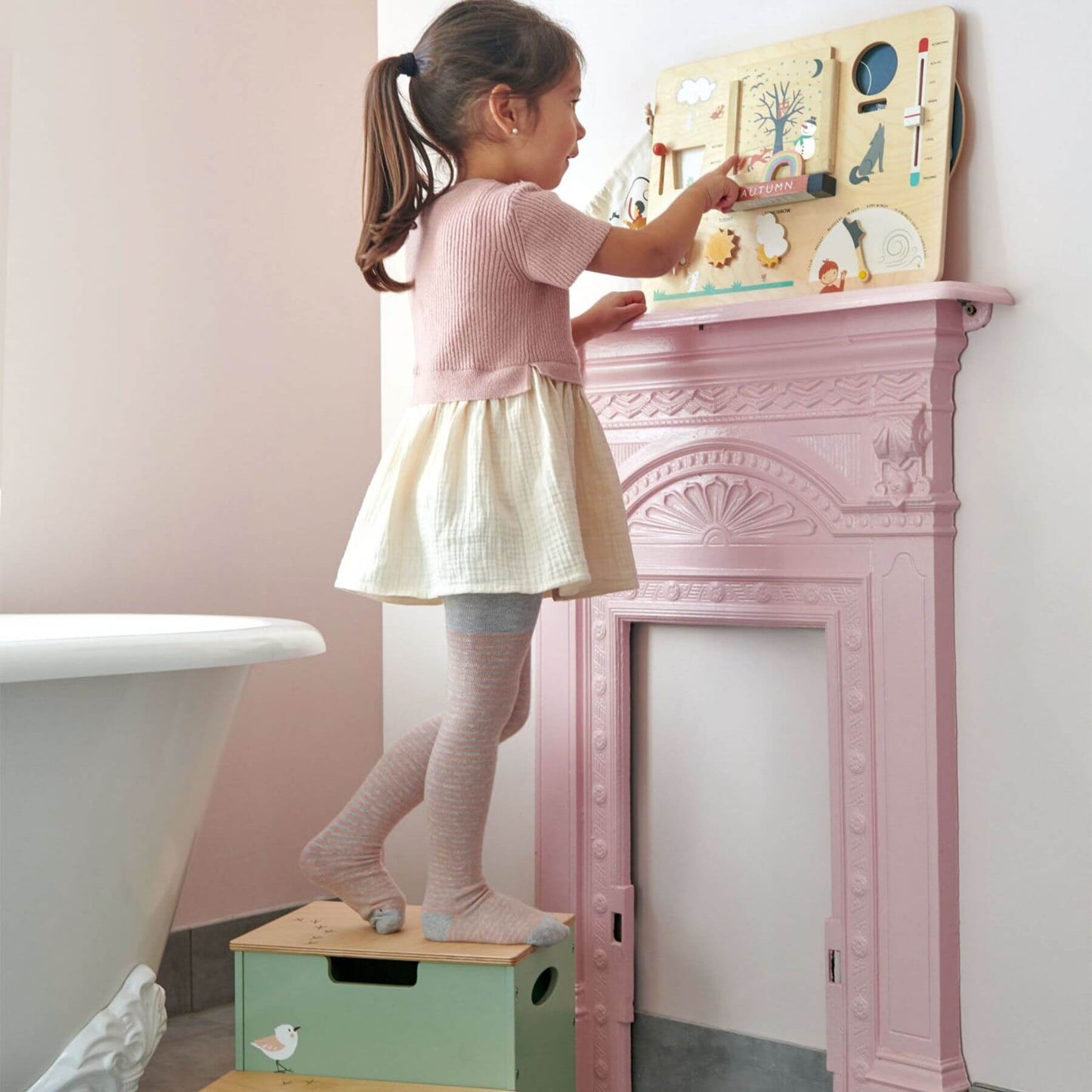 Child playing with Tender Leaf Weather Watch on a pink fireplace