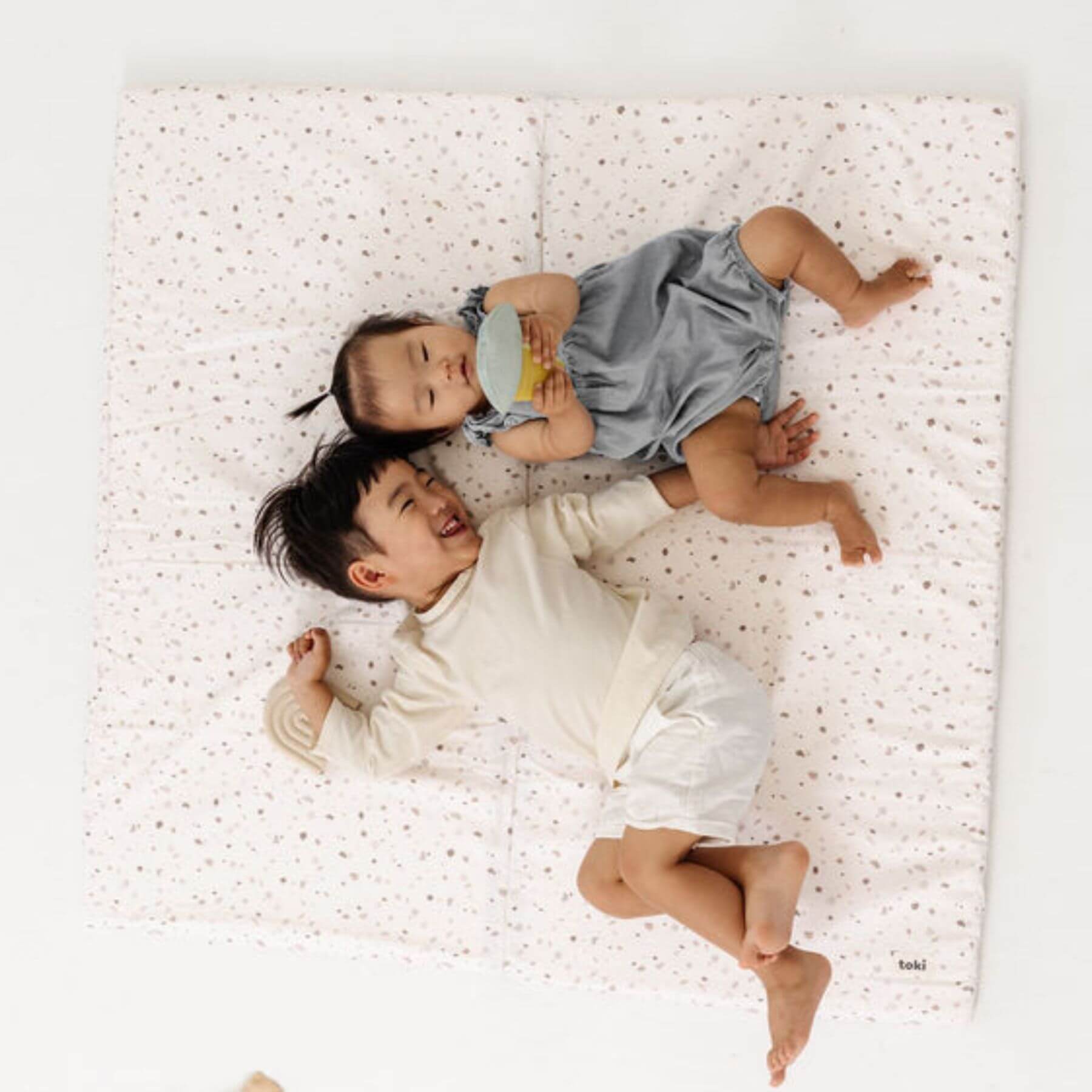 Two children lying on Terrazzo Chalk Organic Cotton Mat