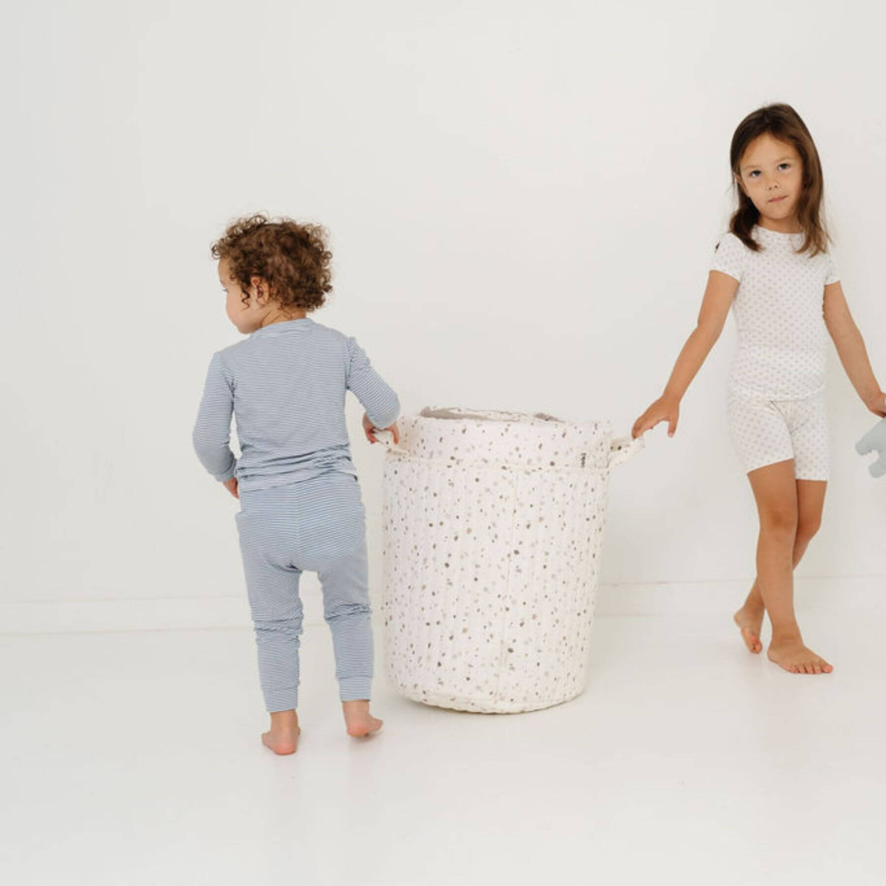 Two children in pajamas standing next to Terrazzo Chalk Storage Basket