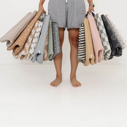 Person holding multiple folded storage baskets with various patterns on a white background