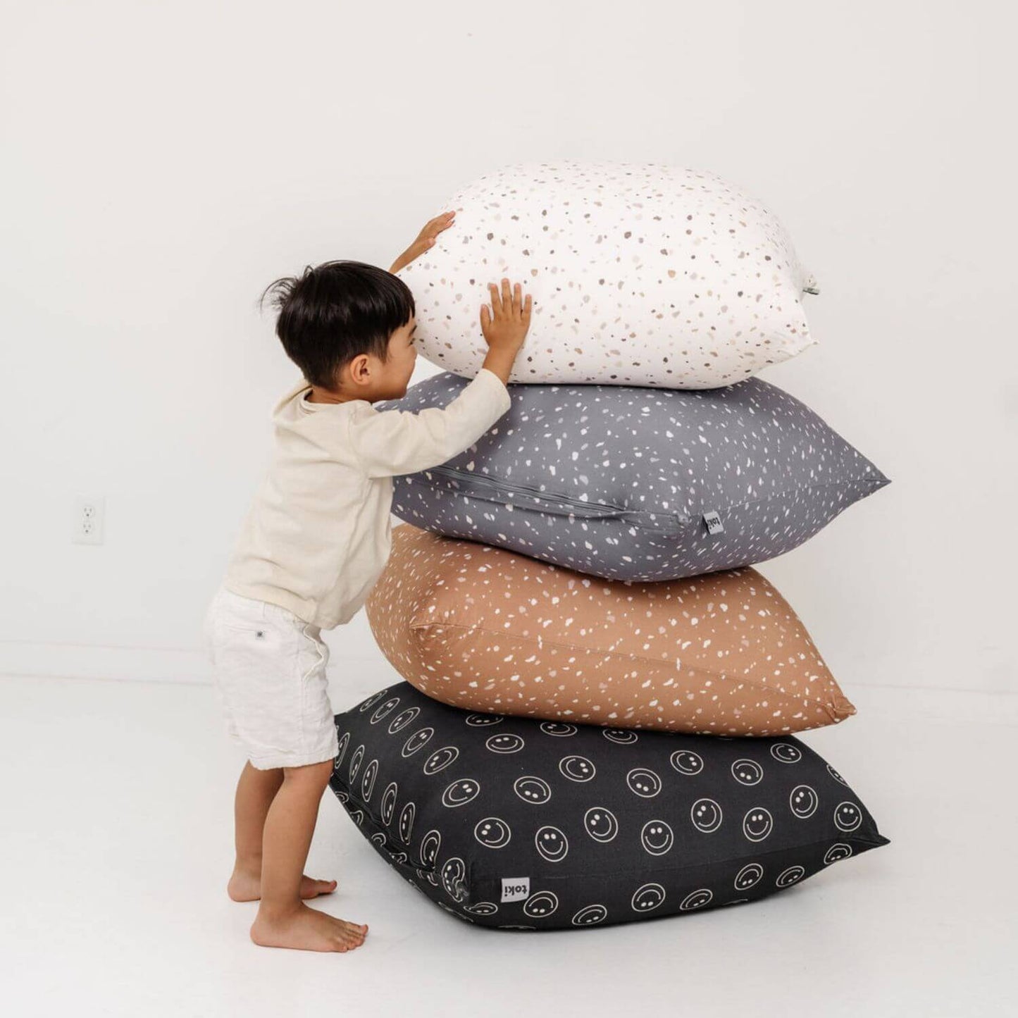 Child playing with a stack of Toki Kids Terrazzo Bean Bags