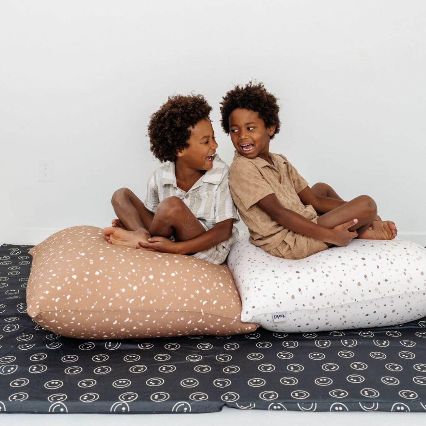 Two children sitting on Toki Kids Terrazzo Bean Bags with a plain background