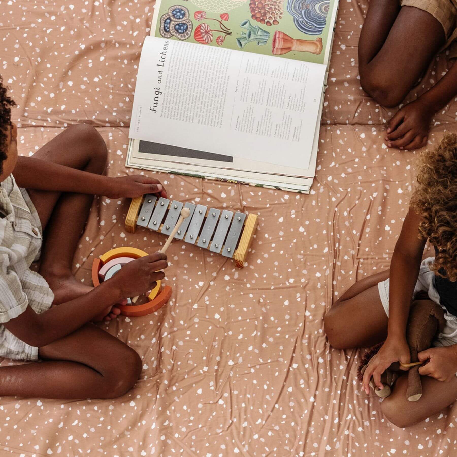 Two children playing with musical instruments on Terrazzo Clay Organic Cotton Mat
