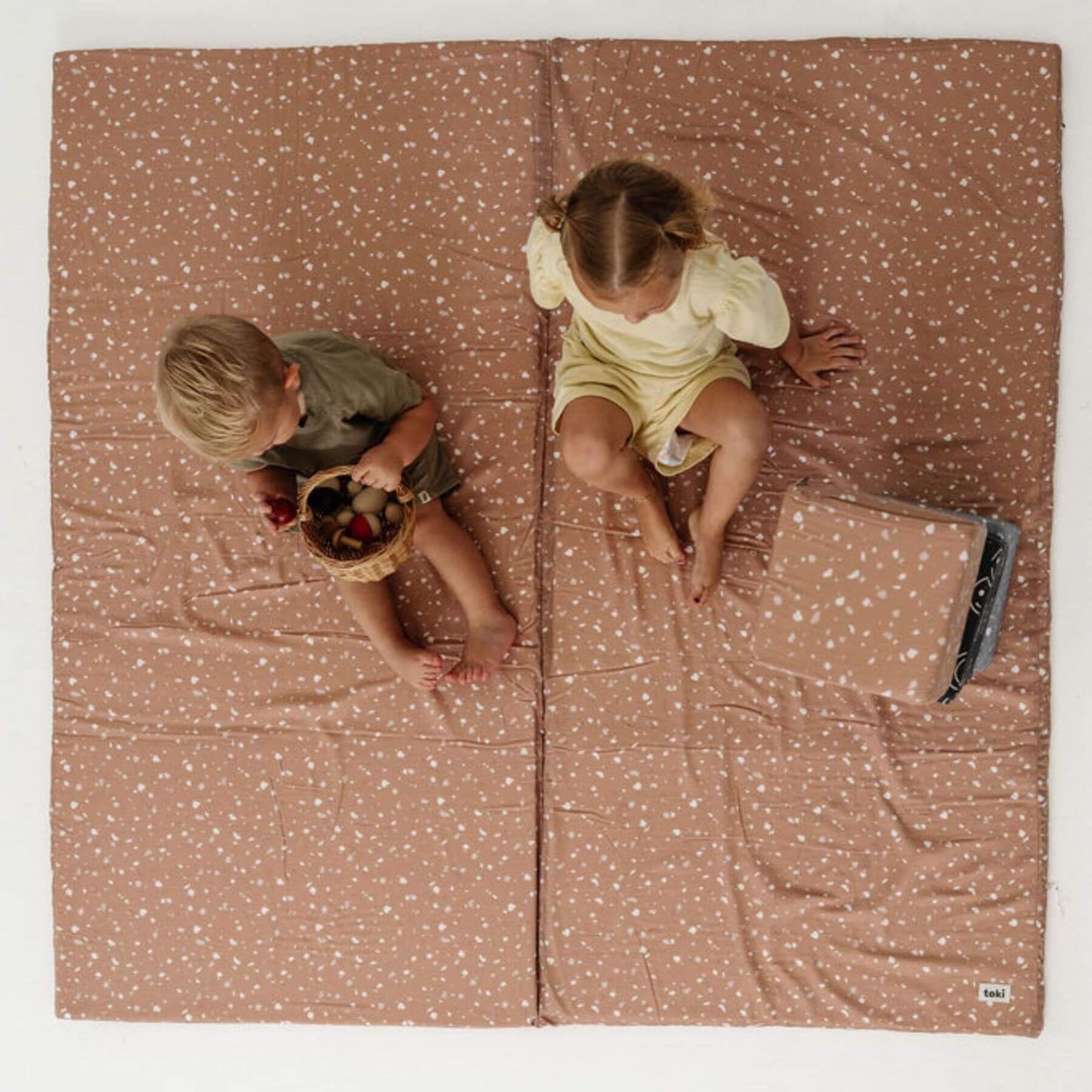 Two children sitting on Terrazzo Clay Organic Cotton Mat