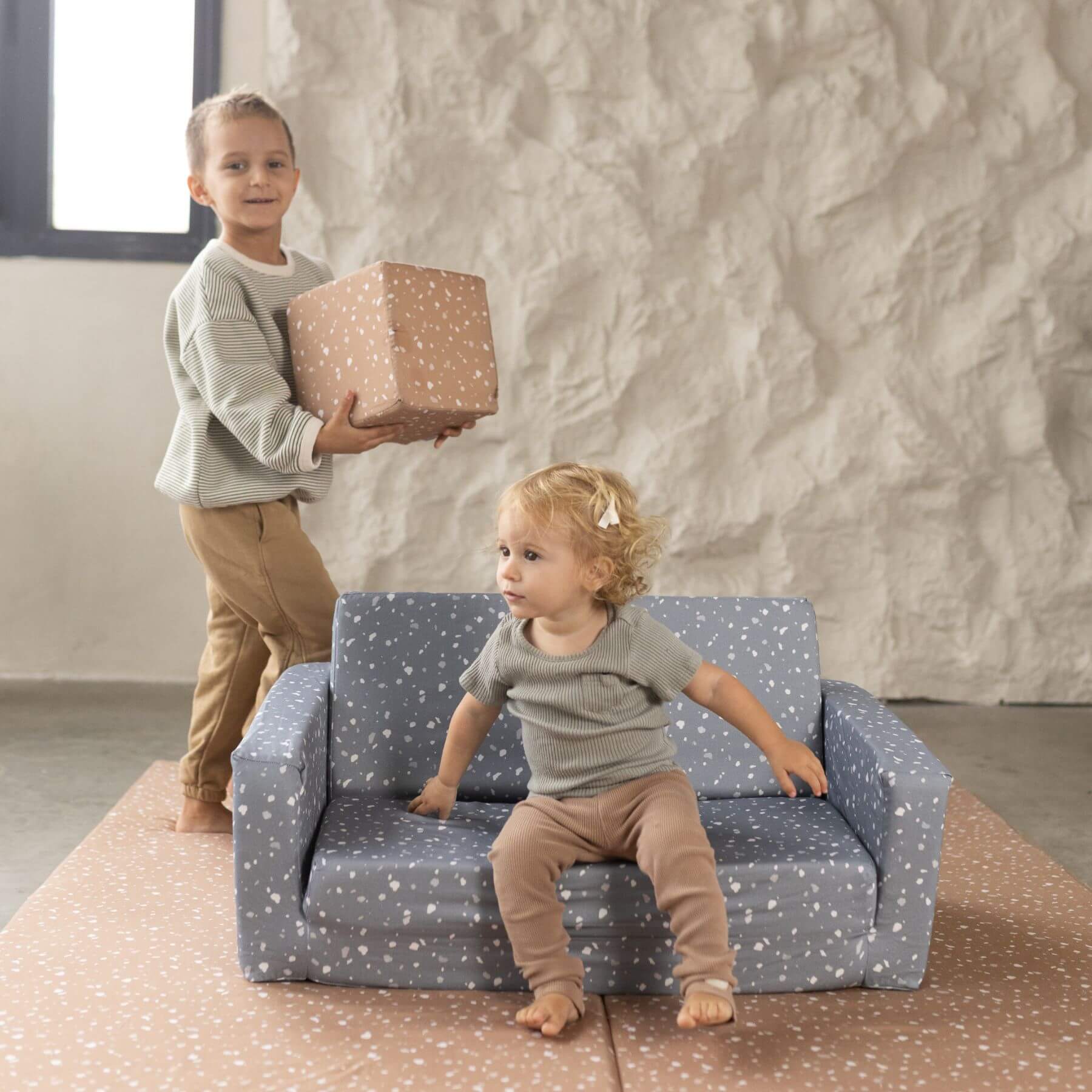 Boy holding Toki Kids Terrazzo Clay Play Cube with girl sitting on play sofa
