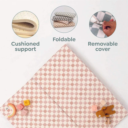 Pink checkered mat with cushioned support, foldable design, and removable cover features on a white background.