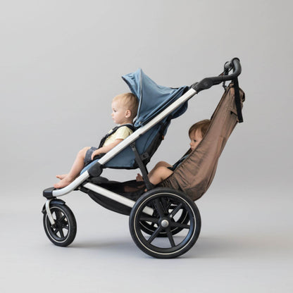 Stroller with a baby in a blue hood and a child in The Stroller Sling on a gray background