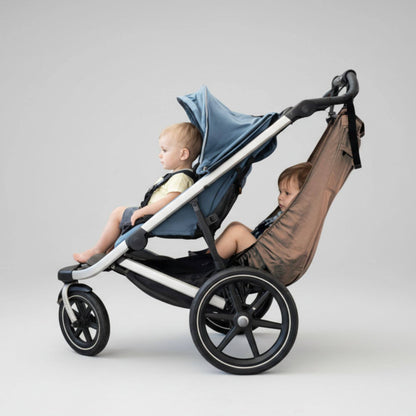 Stroller with two children, one in a car seat and the other in The Stroller Sling, on a light gray background