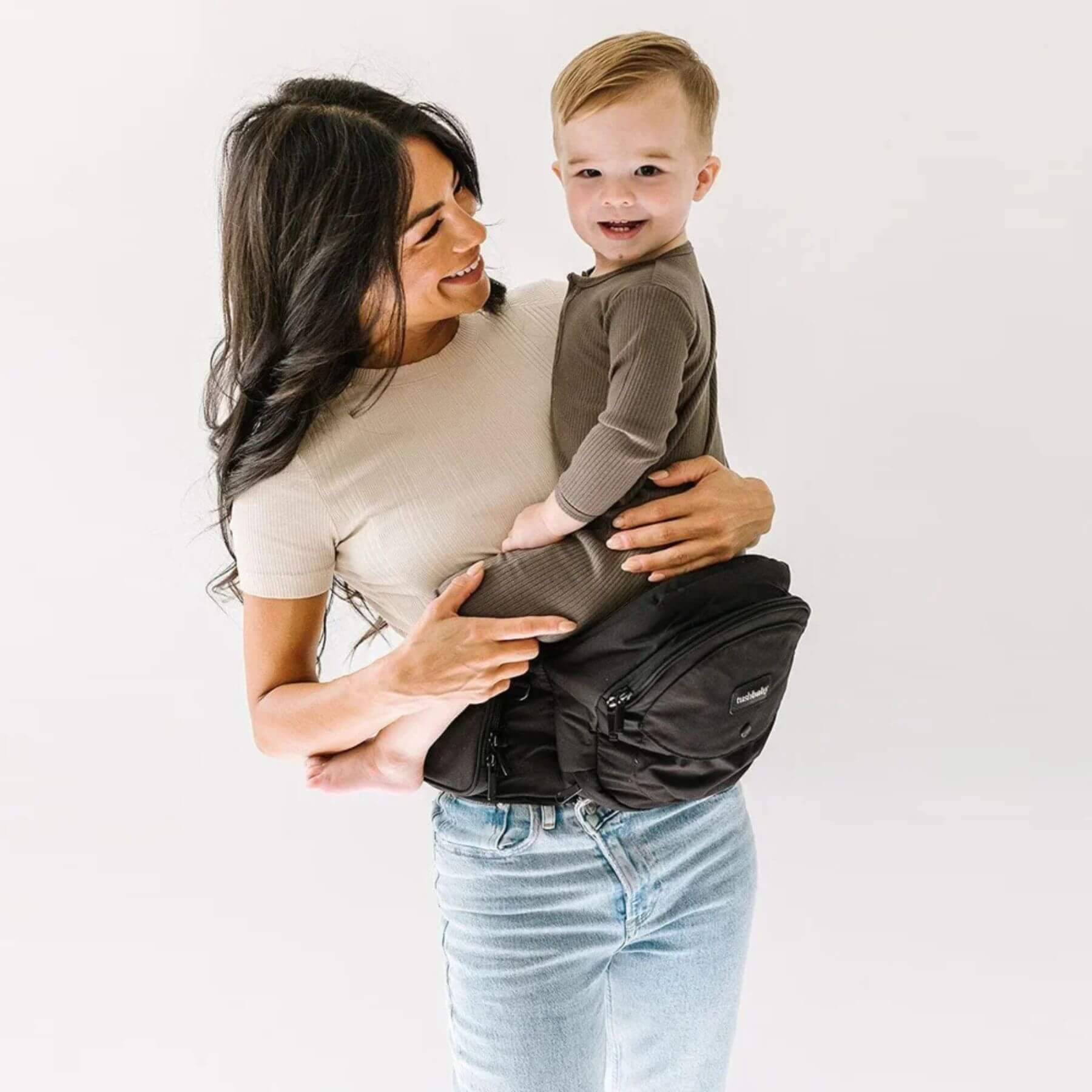 Woman holding a child in The Tushbaby Hip Carrier - Black
