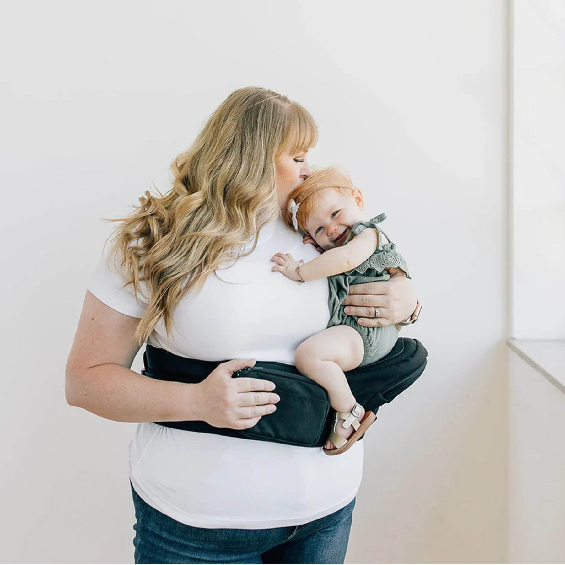 Woman holding a baby in Man holding a baby in The Tushbaby Hip Carrier - Black