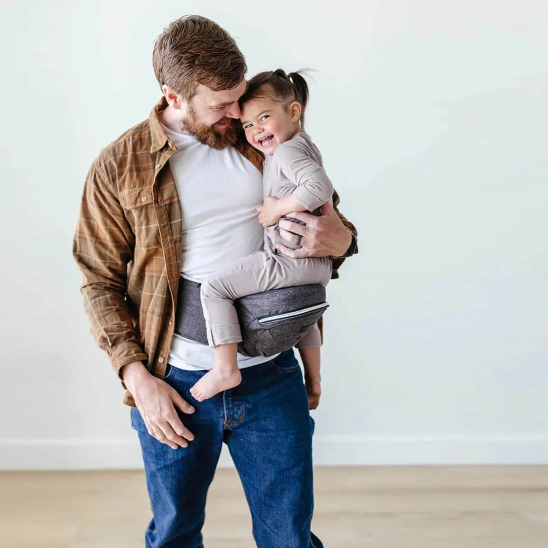 Man holding a child in The Tushbaby Hip Carrier - Charcoal