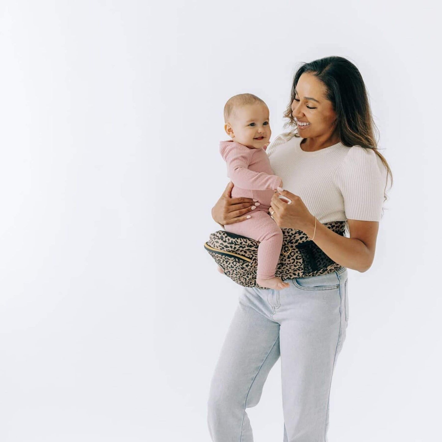 Woman holding a baby with The Tushbaby Hip Carrier - Cheetah