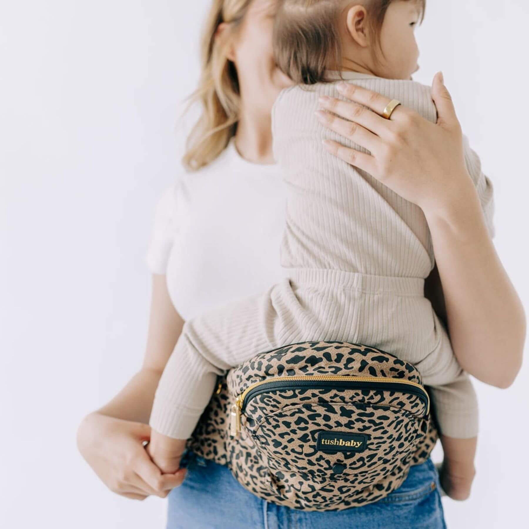 Woman carrying a child with The Tushbaby Hip Carrier - Cheetah