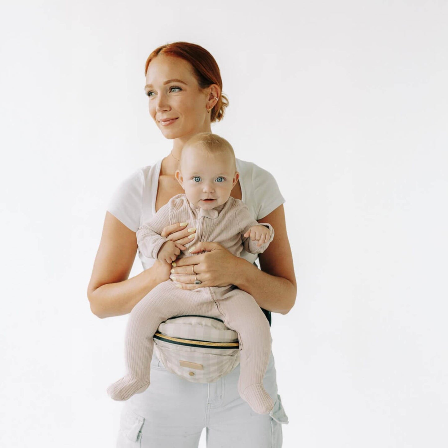 Woman holding a baby in Man holding a baby in The Tushbaby Hip Carrier - Gingham