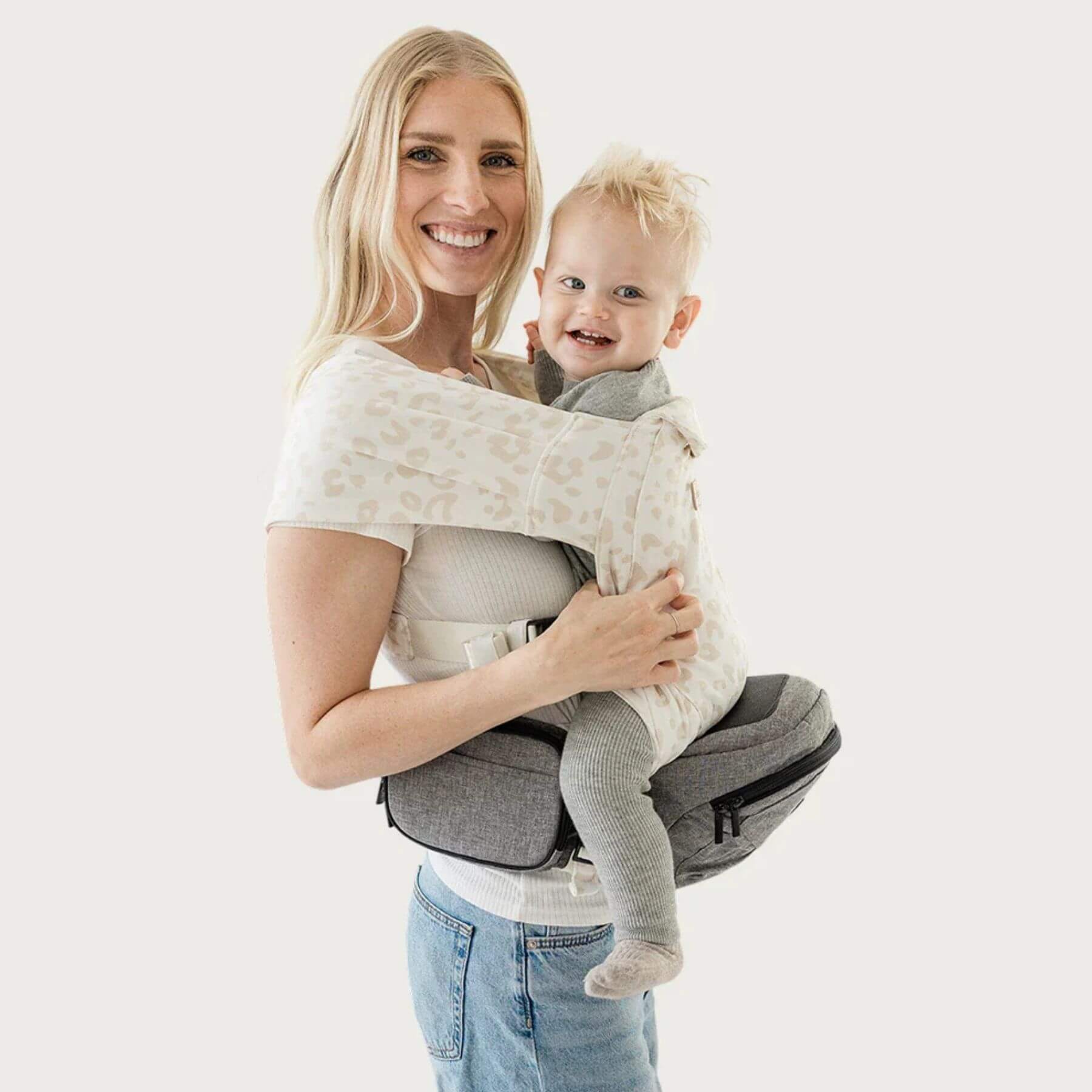 Woman holding a baby in The Tushbaby Hip Carrier - Grey