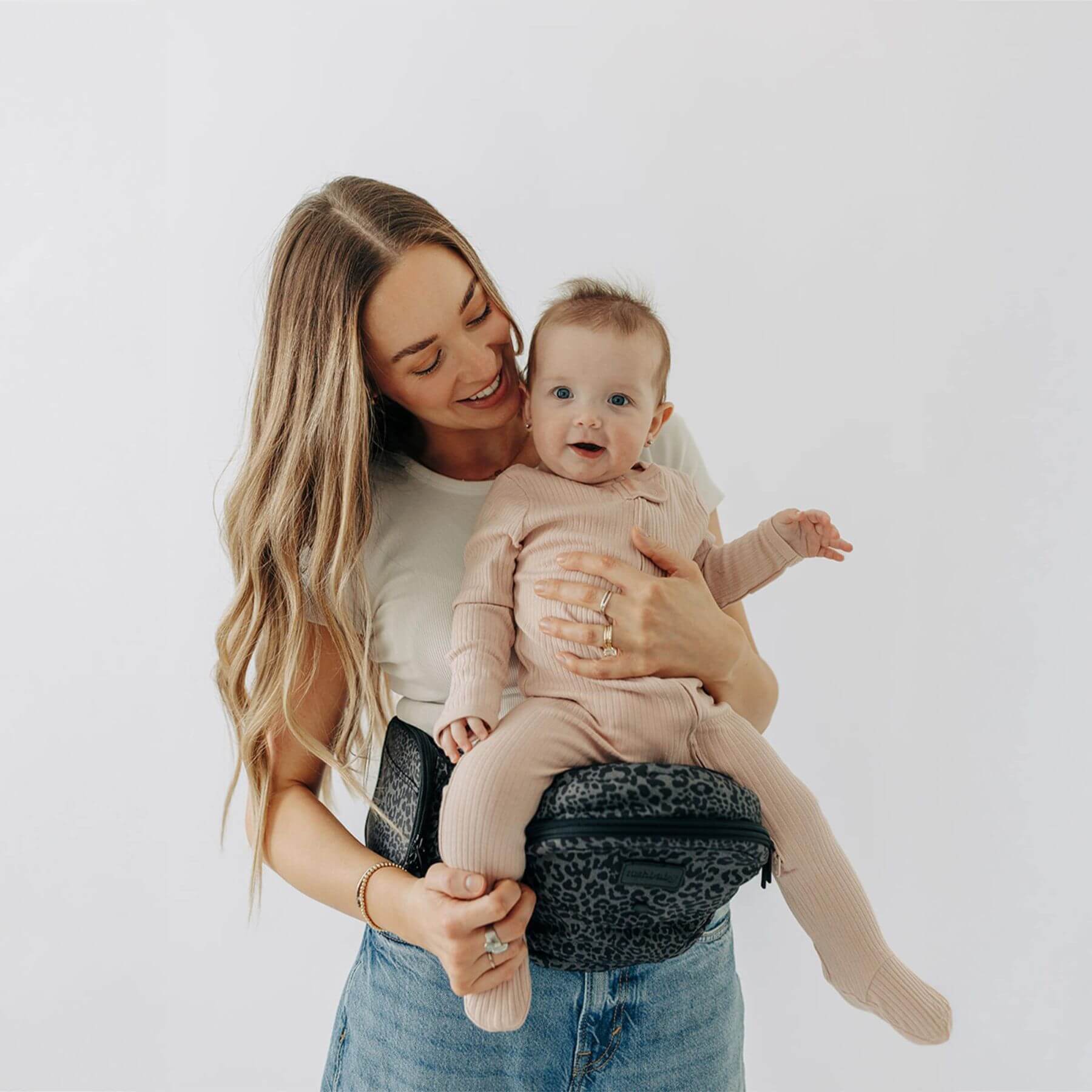 Woman holding a baby in The Tushbaby Hip Carrier - Jaguar