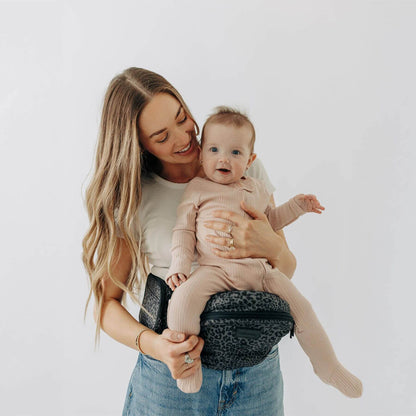 Woman holding a baby in The Tushbaby Hip Carrier - Jaguar