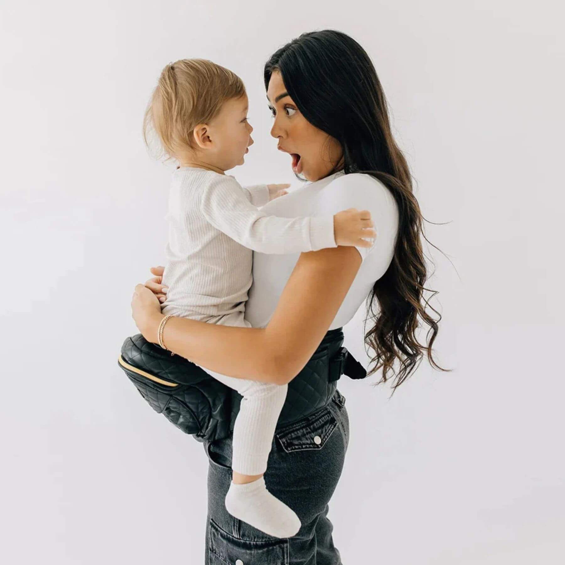 Woman holding a child in The Tushbaby Hip Carrier - Vegan Leather Black