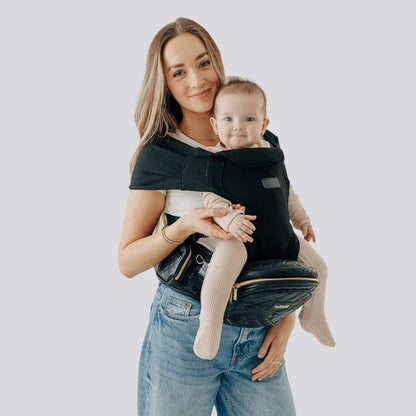 Woman holding a baby in The Tushbaby Hip Carrier - Vegan Leather Black
