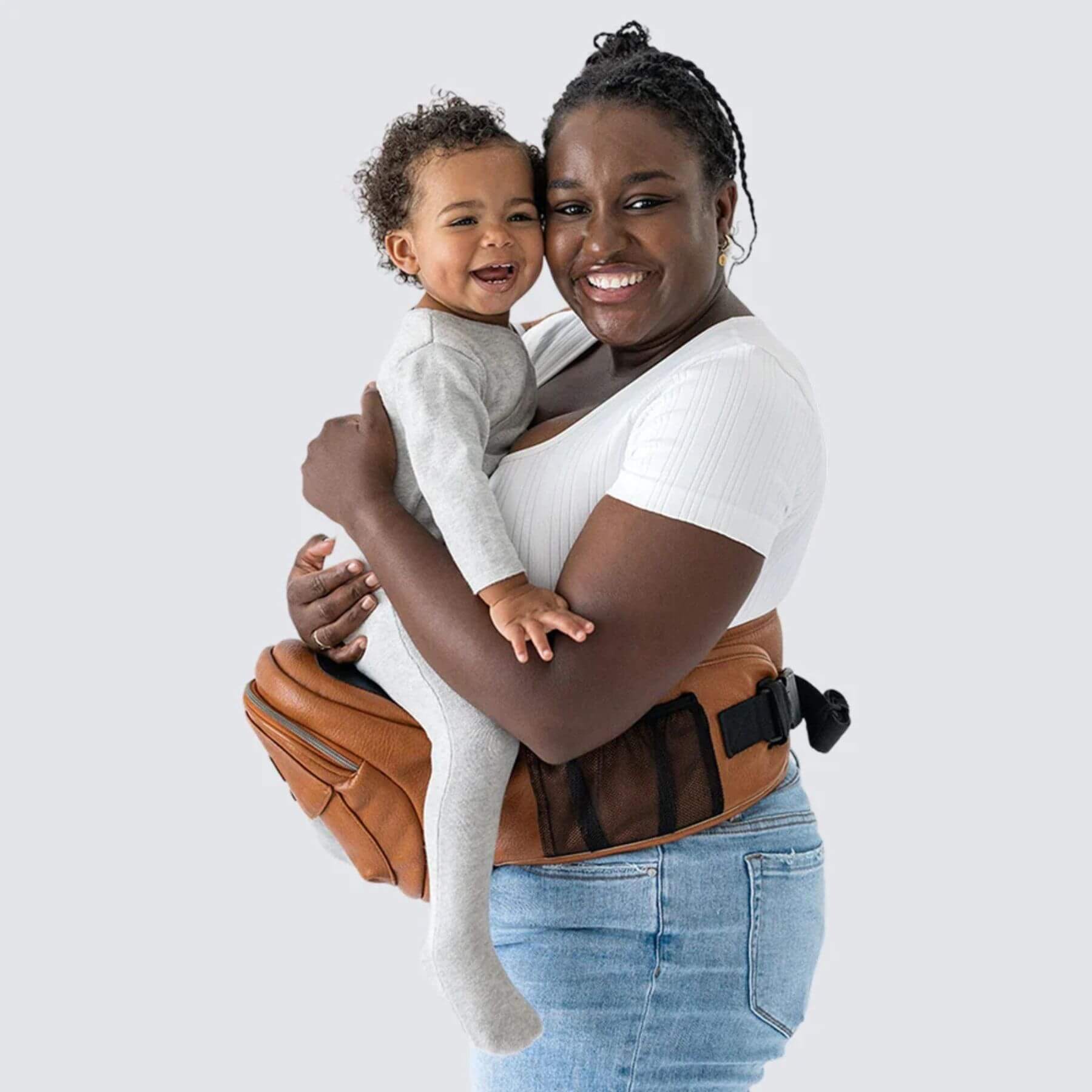 Woman holding a child using The Tushbaby Hip Carrier - Vegan Leather Cognac