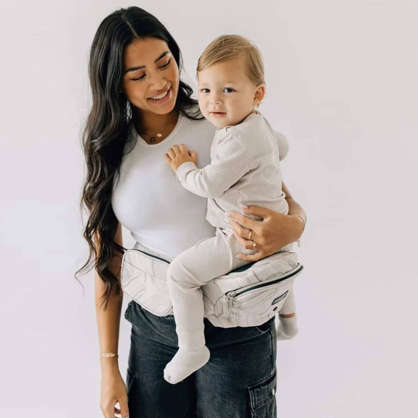 Woman holding a baby in The Tushbaby Hip Carrier - Marbel