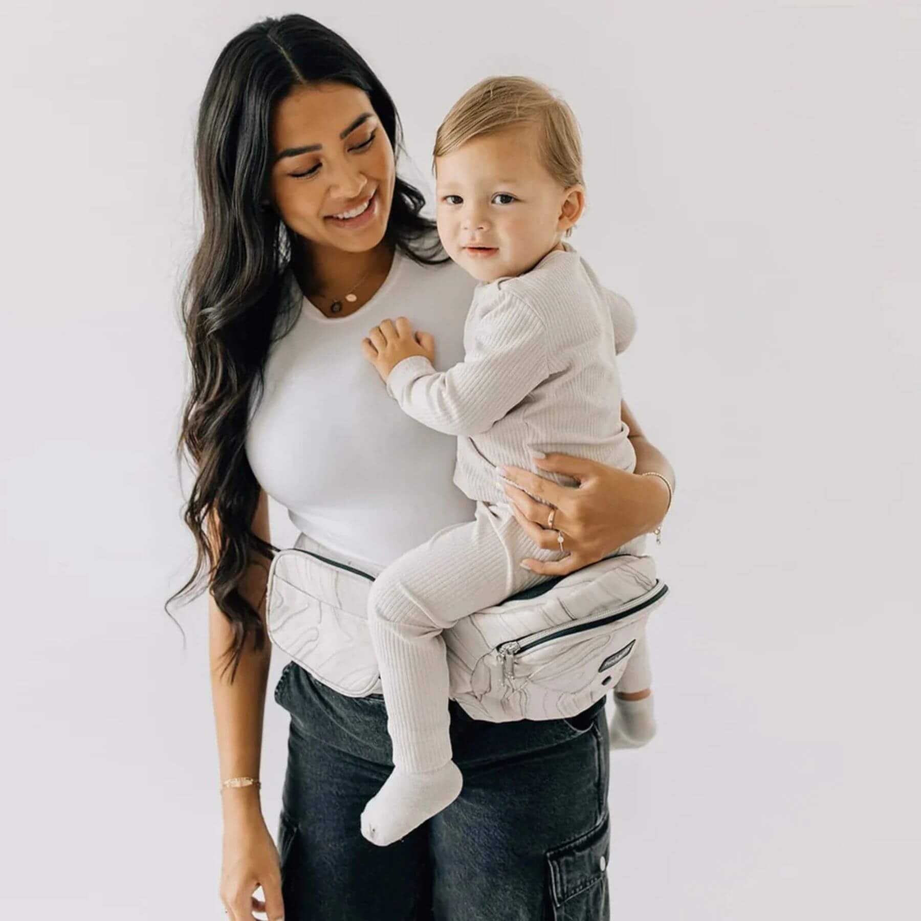 Woman holding a baby in The Tushbaby Hip Carrier - Marbel