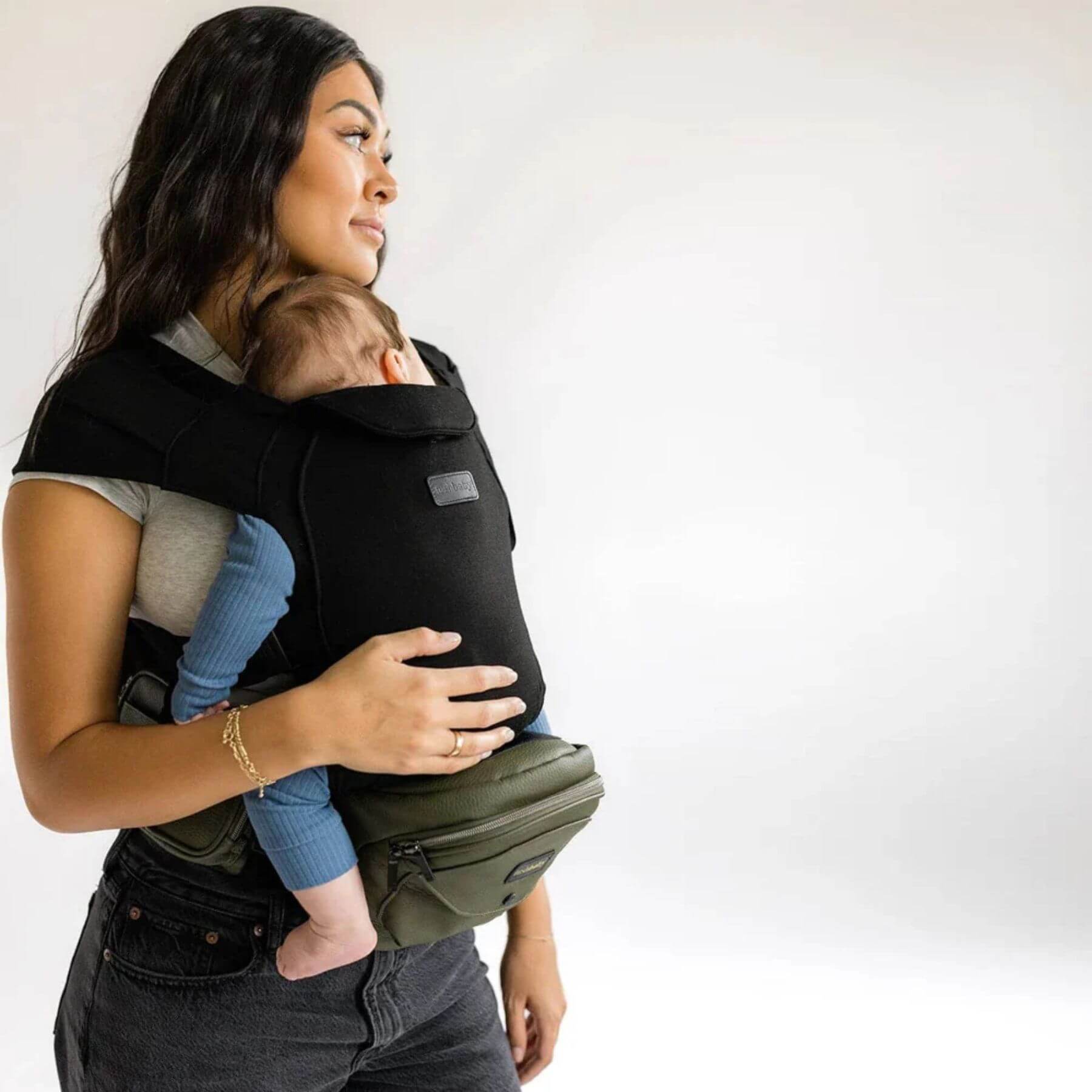 Woman holding a baby in The Tushbaby Hip Carrier - Olive