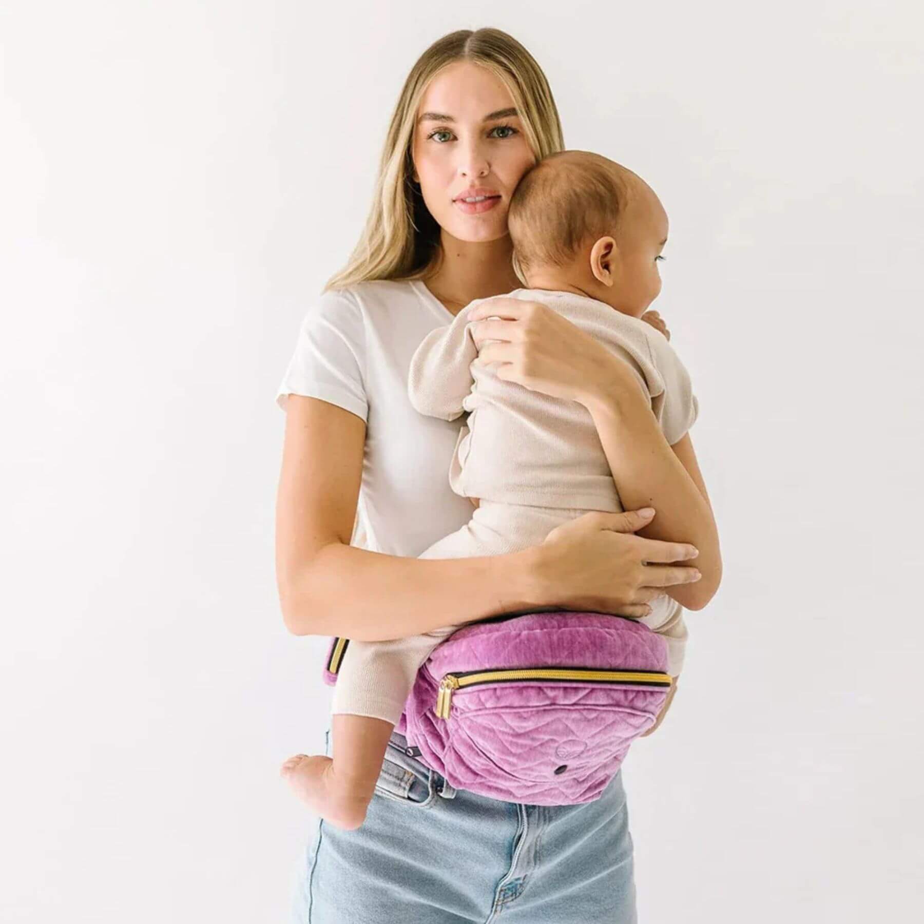 Woman holding a baby with The Tushbaby Hip Carrier - Orchid