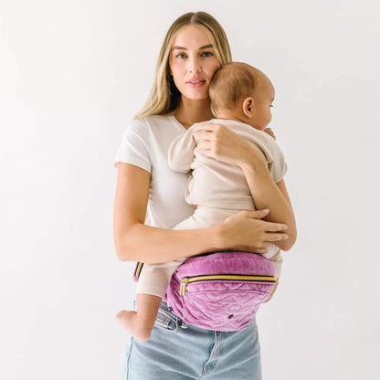 Woman holding a baby with The Tushbaby Hip Carrier - Orchid