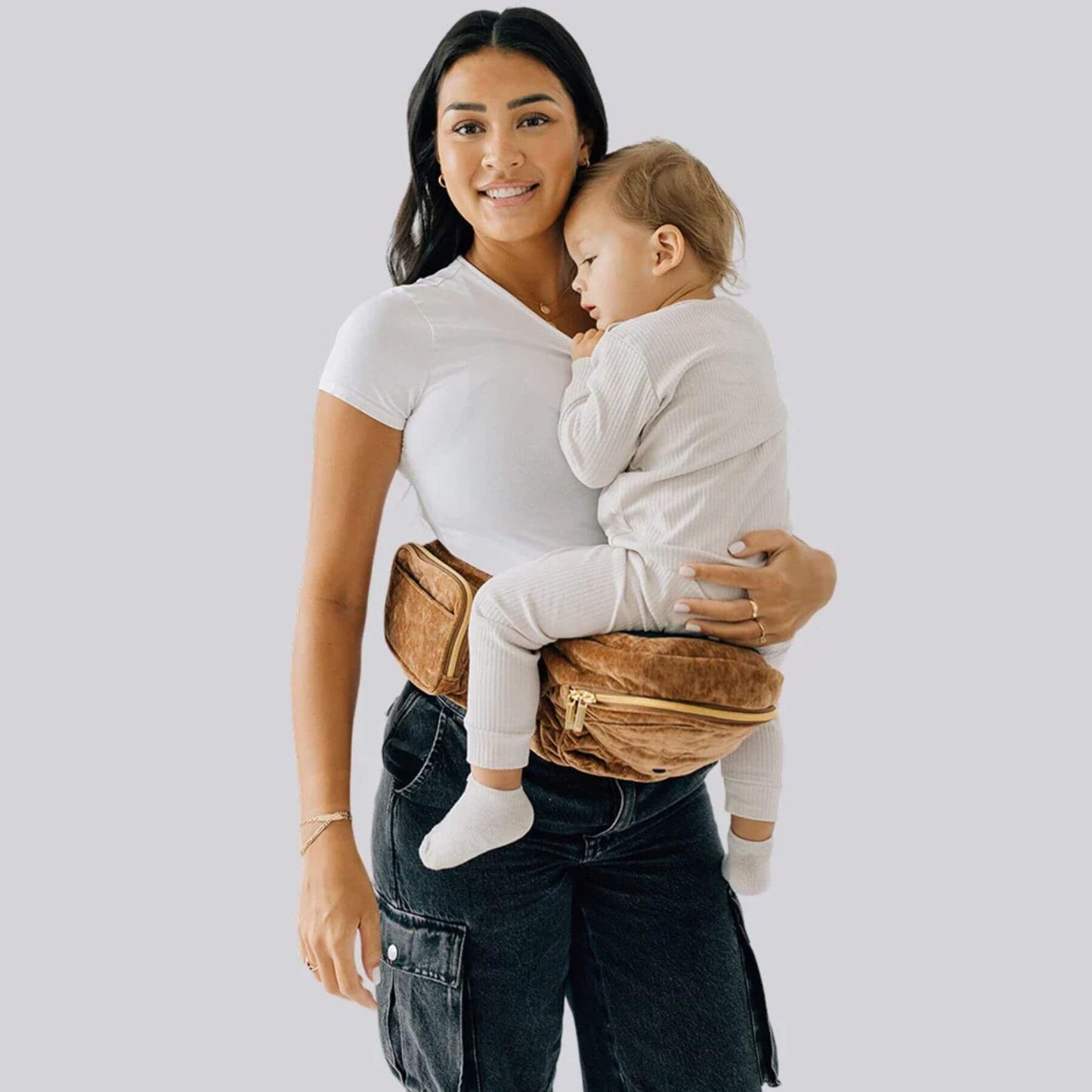 Woman holding a baby in The Tushbaby Hip Carrier - Sable