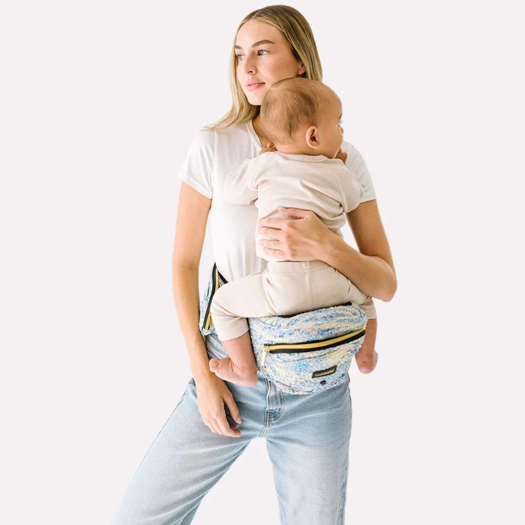 Woman holding a baby in The Tushbaby Hip Carrier - Tweed