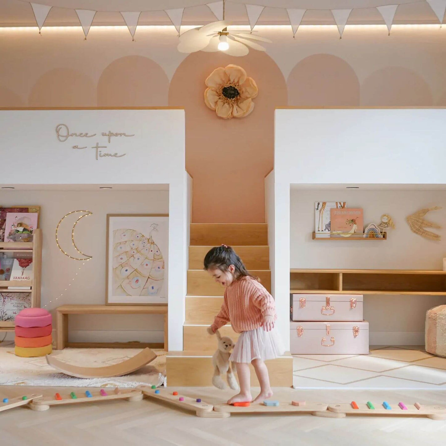 Child playing with Tiny Land® Balance Beam in a playroom with wooden furniture and decorative elements.