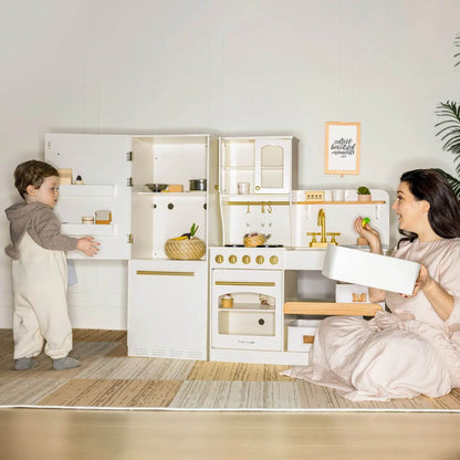 Two children playing with a toy kitchen set in a room.
