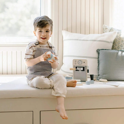 Child sitting on a window sill holding a toy, with Tiny Land® Children’s Coffee Maker