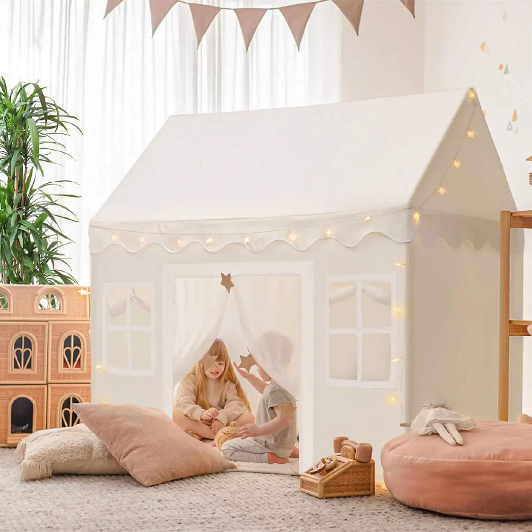 Children playing inside Tiny Land® Playhouse Tent – Natural Cream with toys and cushions in a room.