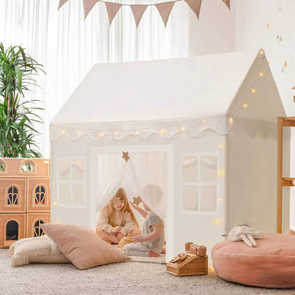 Children playing inside Tiny Land® Playhouse Tent – Natural Cream with toys and cushions in a room.