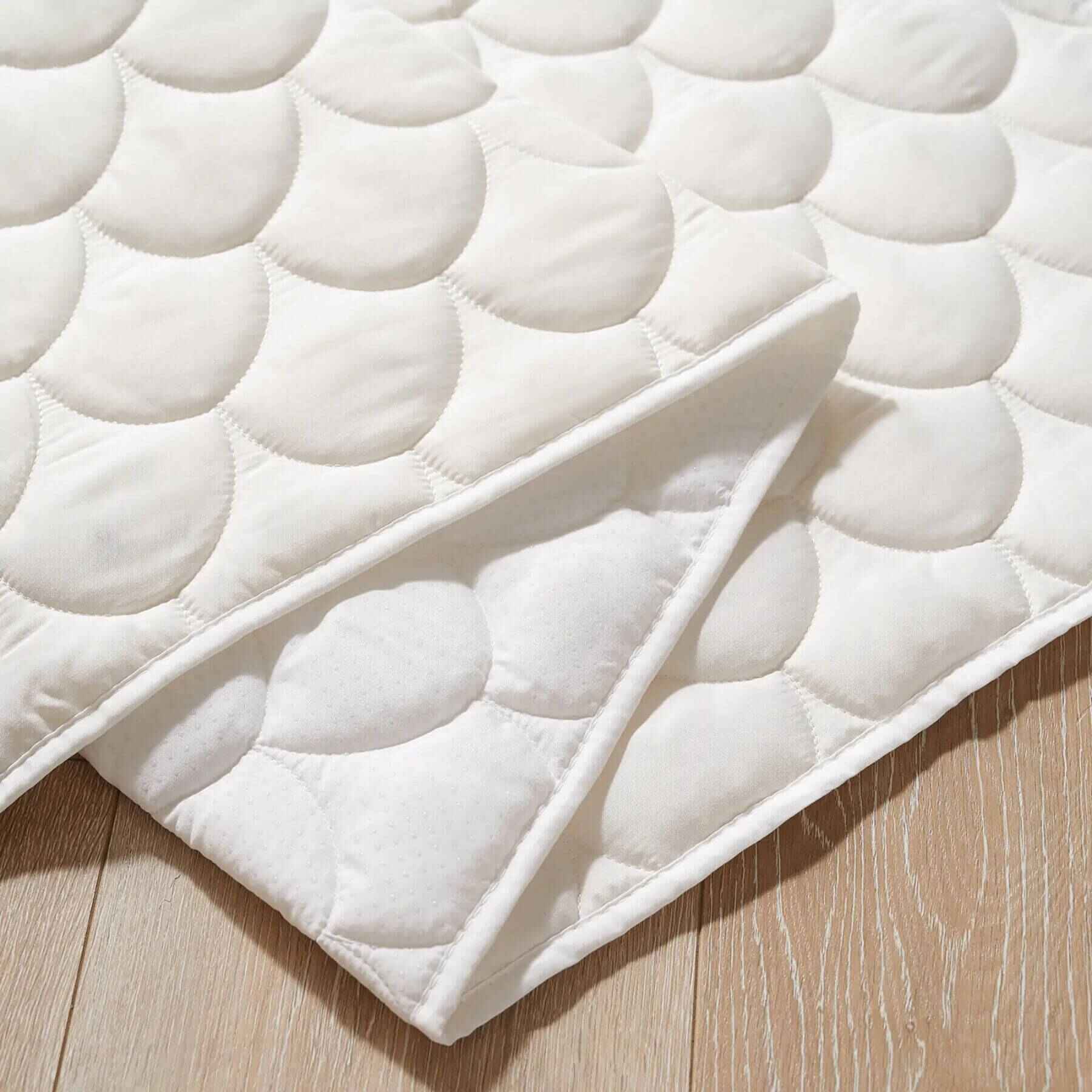 White quilted mattress topper on a wooden surface