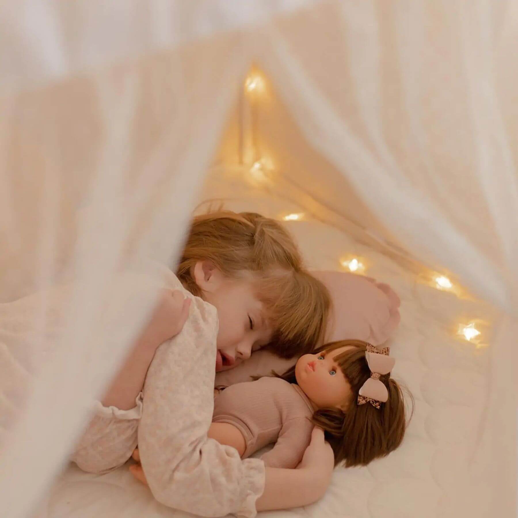 Child hugging a doll under Tiny Land® Playhouse Tent – Natural Cream