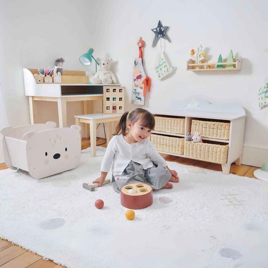Child playing with toys in a playroom with wooden furniture and decor.