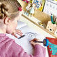 Child drawing a picture with toys and educational materials on a desk