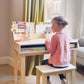 Child sitting at Tender Leaf Desk and Chair with educational materials in a home setting
