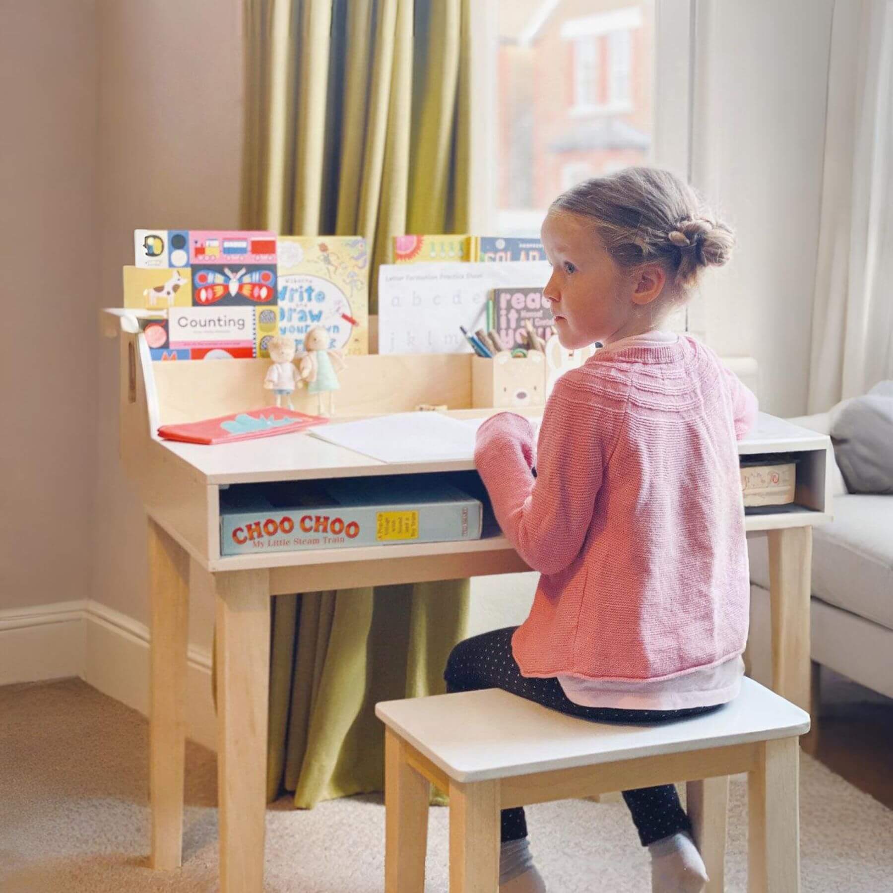 Child sitting at Tender Leaf Desk and Chair with educational materials in a home setting