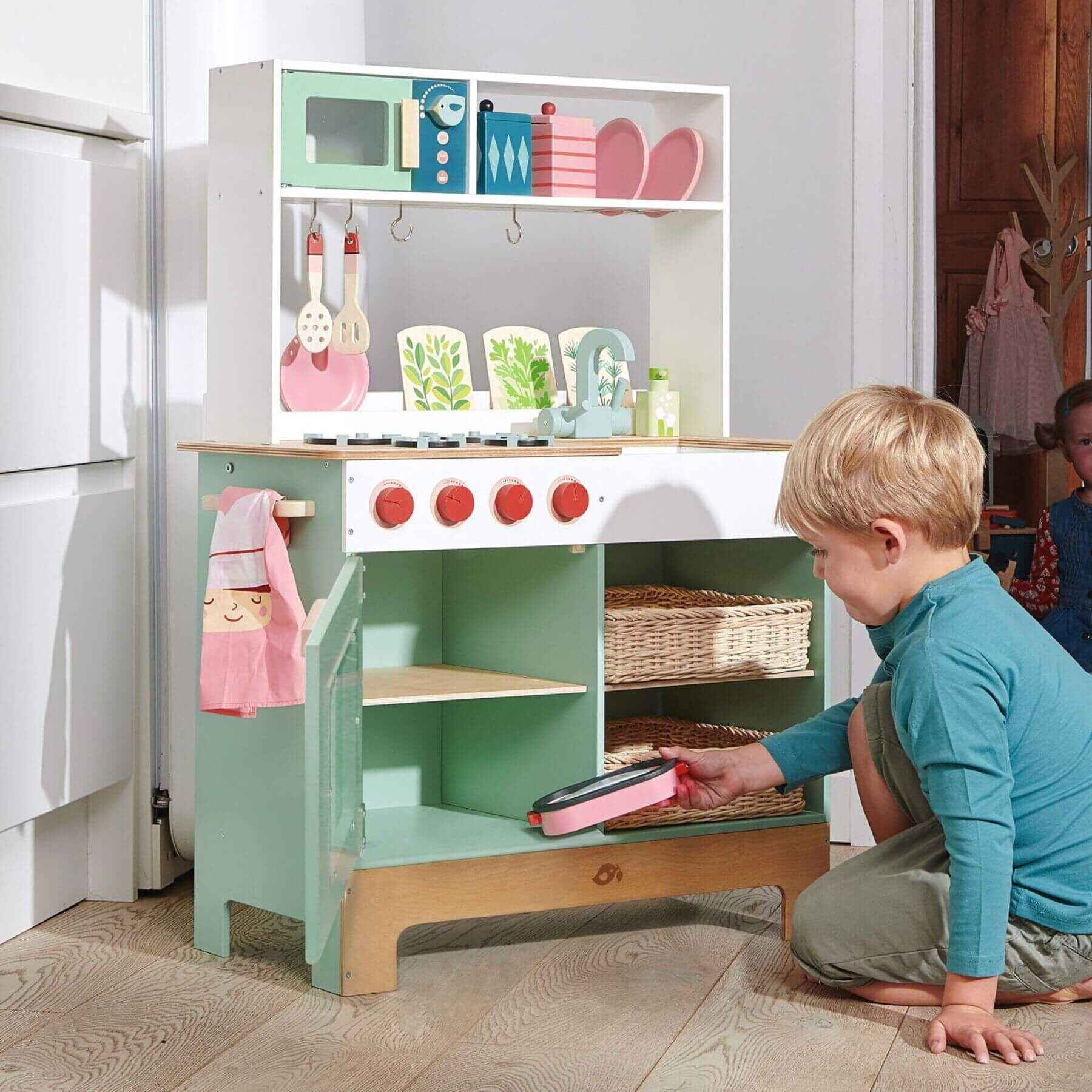 Child playing with Tender Leaf Kitchen Range in a room.