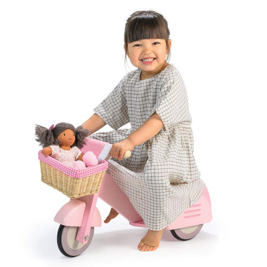 Child on Tender Leaf Scooter with Basket, wearing a checkered dress.
