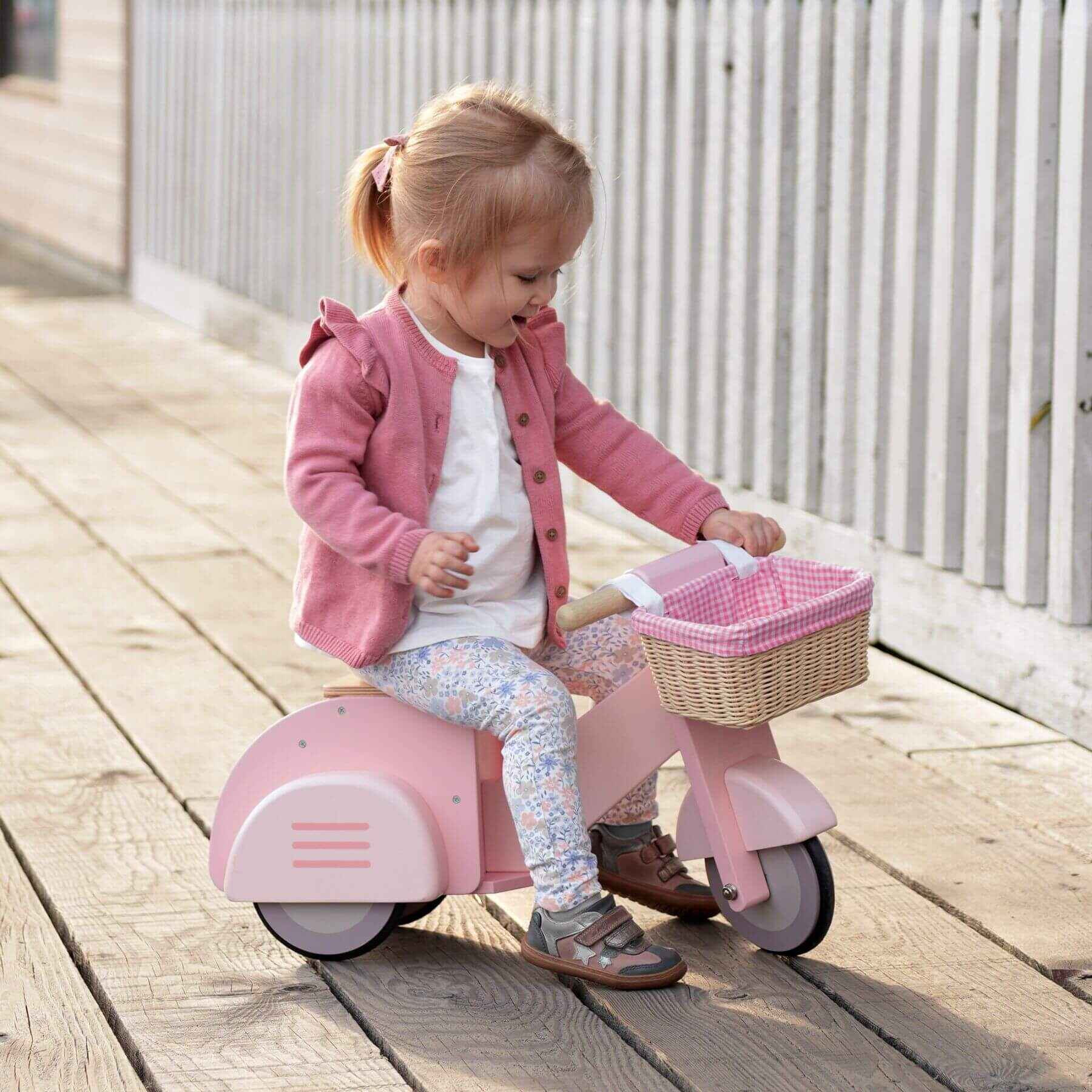 Child on Tender Leaf Scooter with Basket on a wooden deck