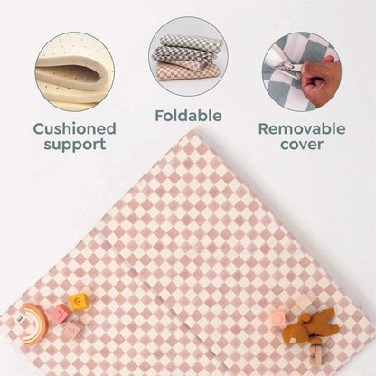 Pink checkered mat with cushioned support, foldable design, and removable cover features on a white background.