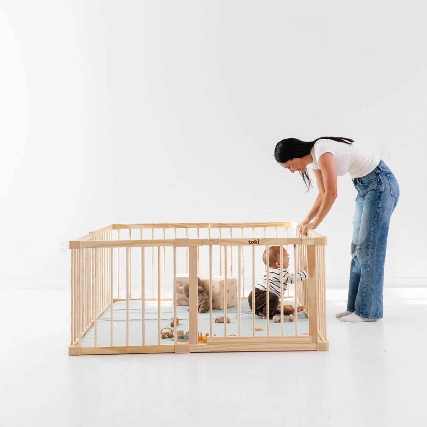 Baby playing in Toki Kids Playpen - Mega Size in Wood with woman standing outside
