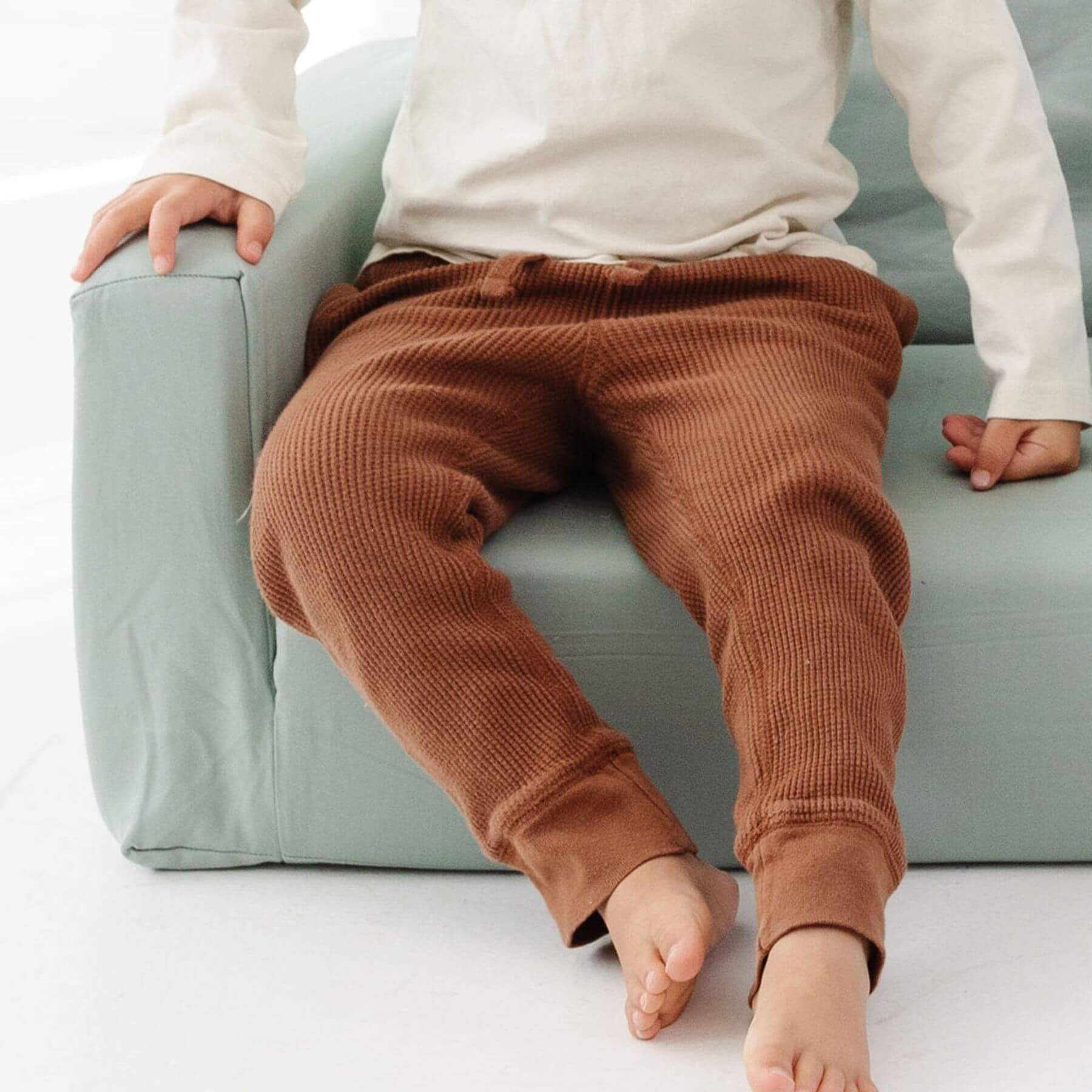 Person wearing brown ribbed pants sitting on Toki Kids Sage Play Couch